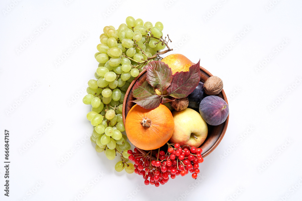 Bowl with different fresh fruits, berries and pumpkin on white background