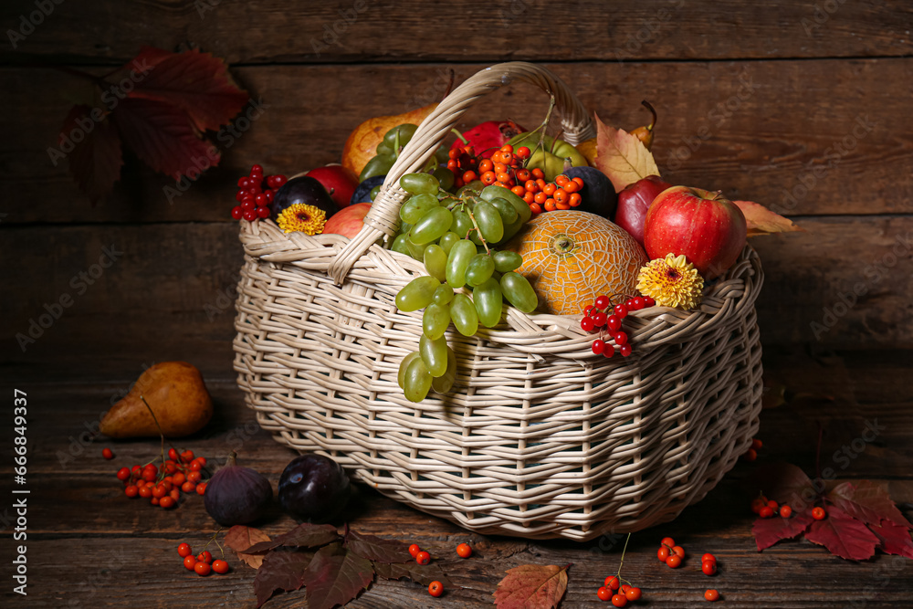 Wicker basket with different fresh fruits on wooden background