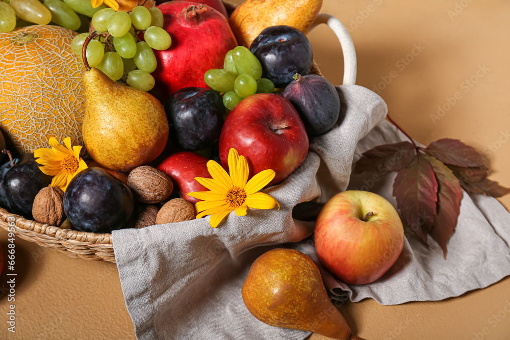 Wicker basket with different fresh fruits on beige background