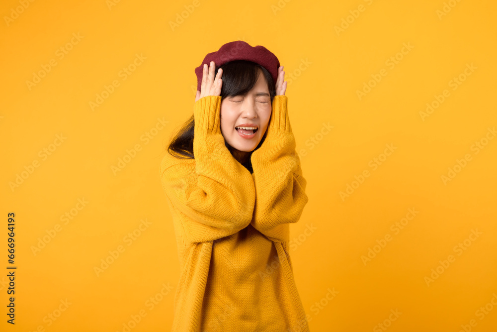 Amidst the noise, a stylish Asian lady, dressed in a yellow sweater and red beret, listens attentively against a vibrant yellow setting.