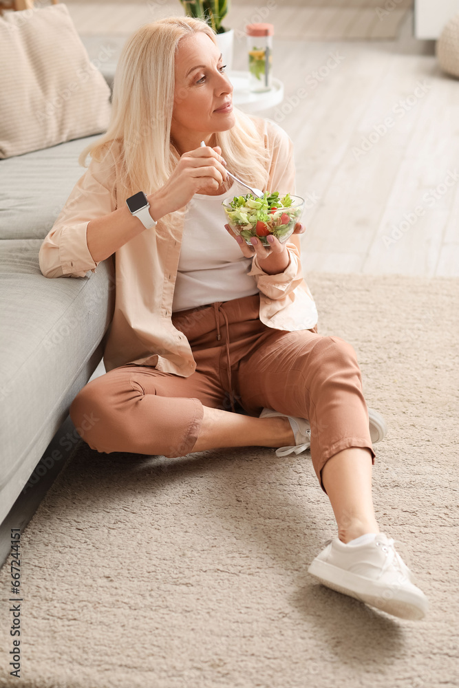 Mature woman eating vegetable salad at home