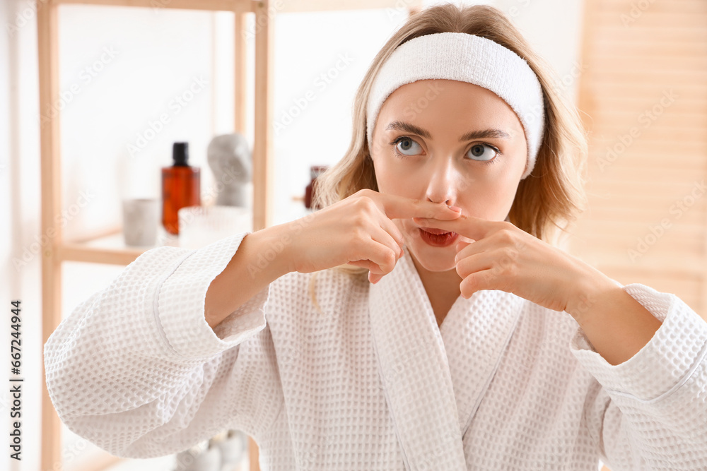 Young woman doing face building exercise in bathroom, closeup