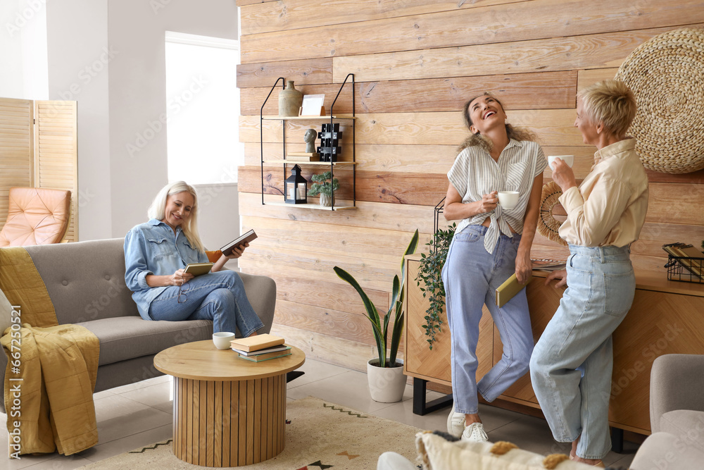 Mature women with tea taking part in book club at home