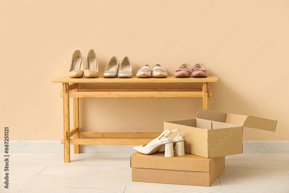 Stylish female shoes on wooden table near color wall