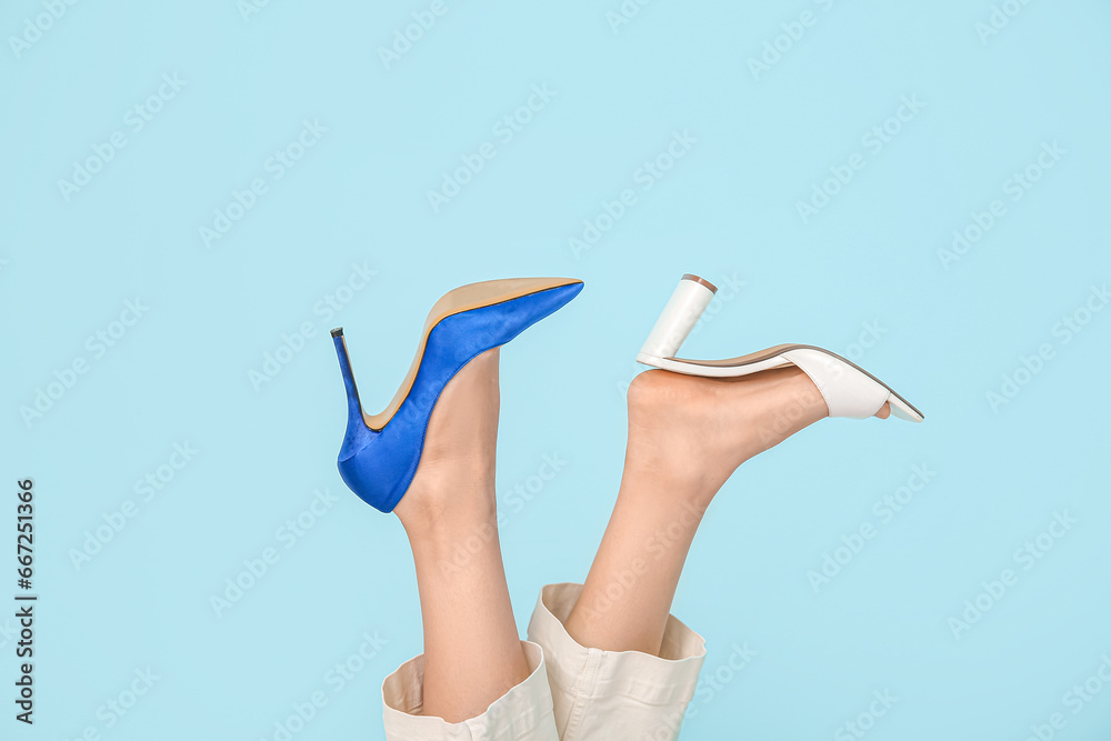 Female legs in different high heeled shoes on color background