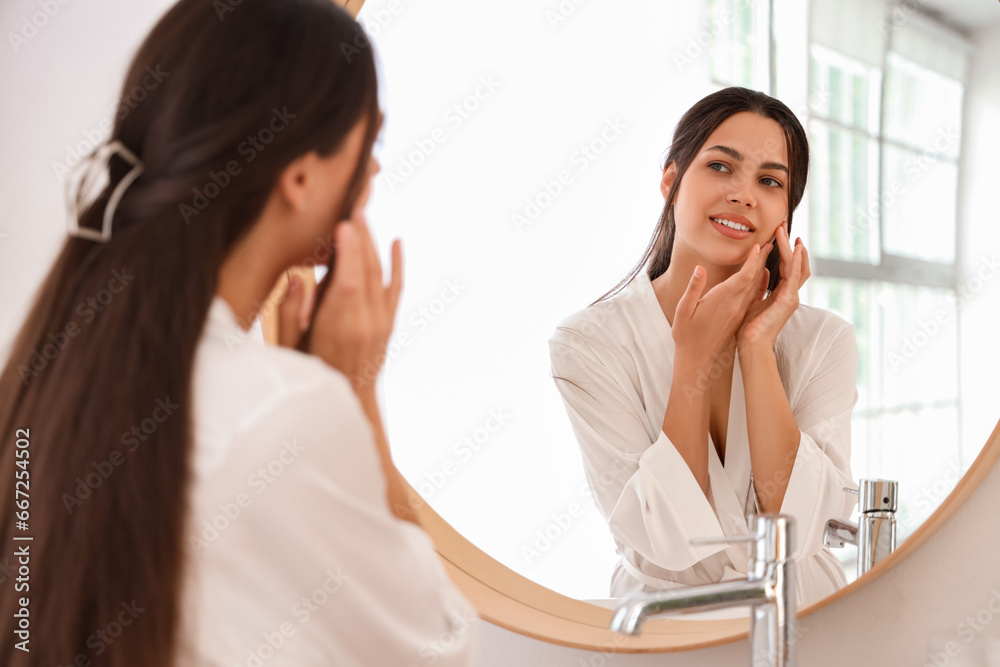 Young woman near mirror in bathroom