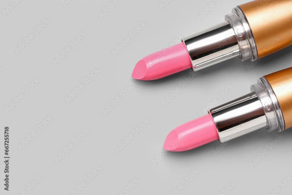 Stylish pink lipsticks on light background, closeup