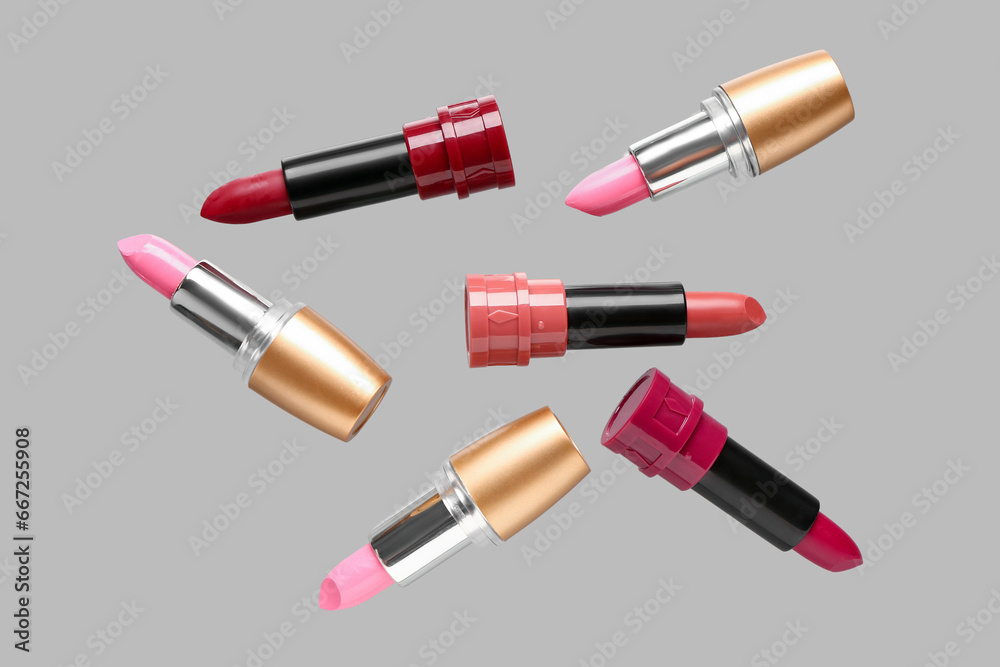 Lipsticks flying on grey background