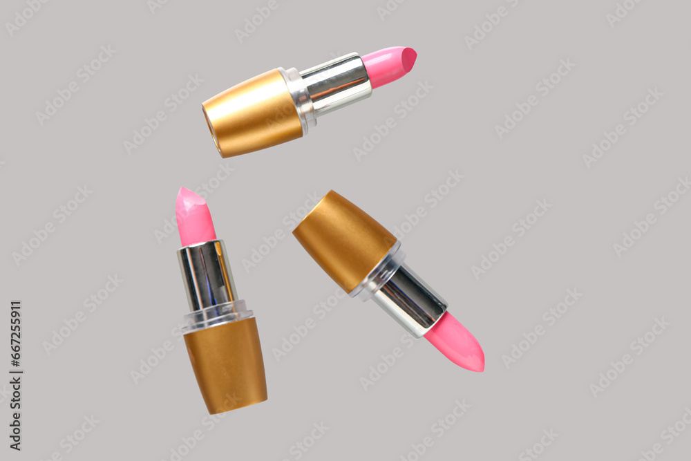 Lipsticks flying on grey background