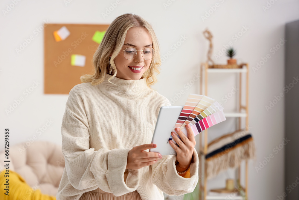 Female interior designer with tablet computer and color palettes in office