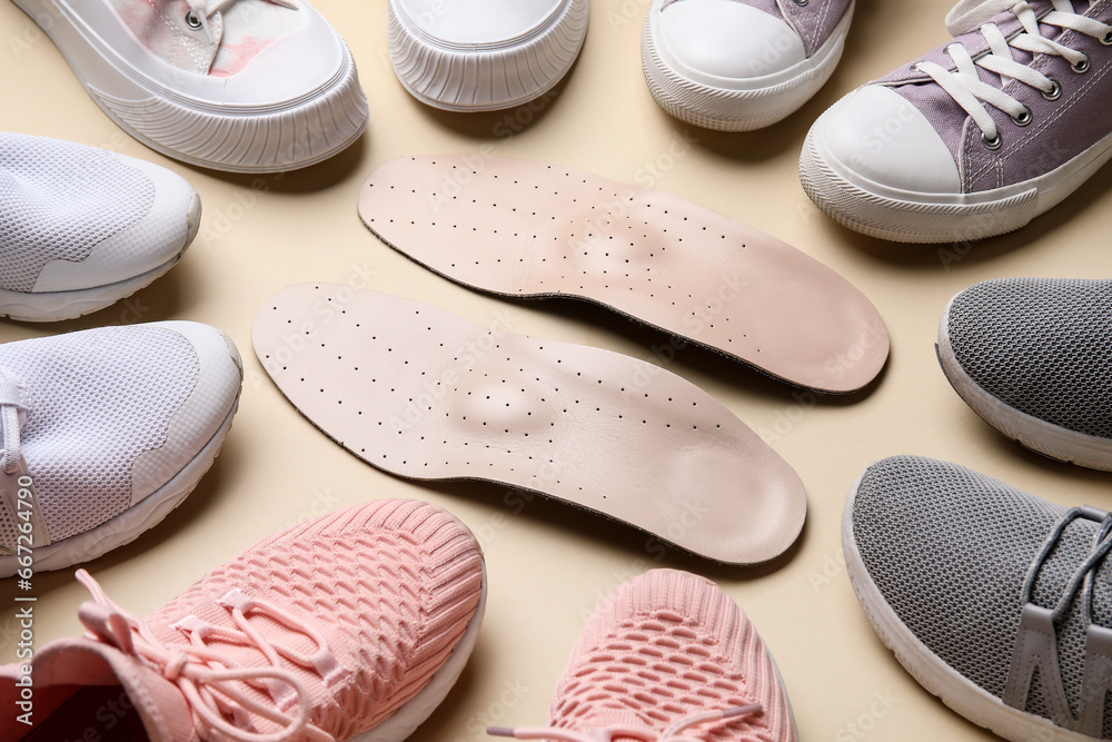 Composition with different sneakers and orthopedic insoles on beige background