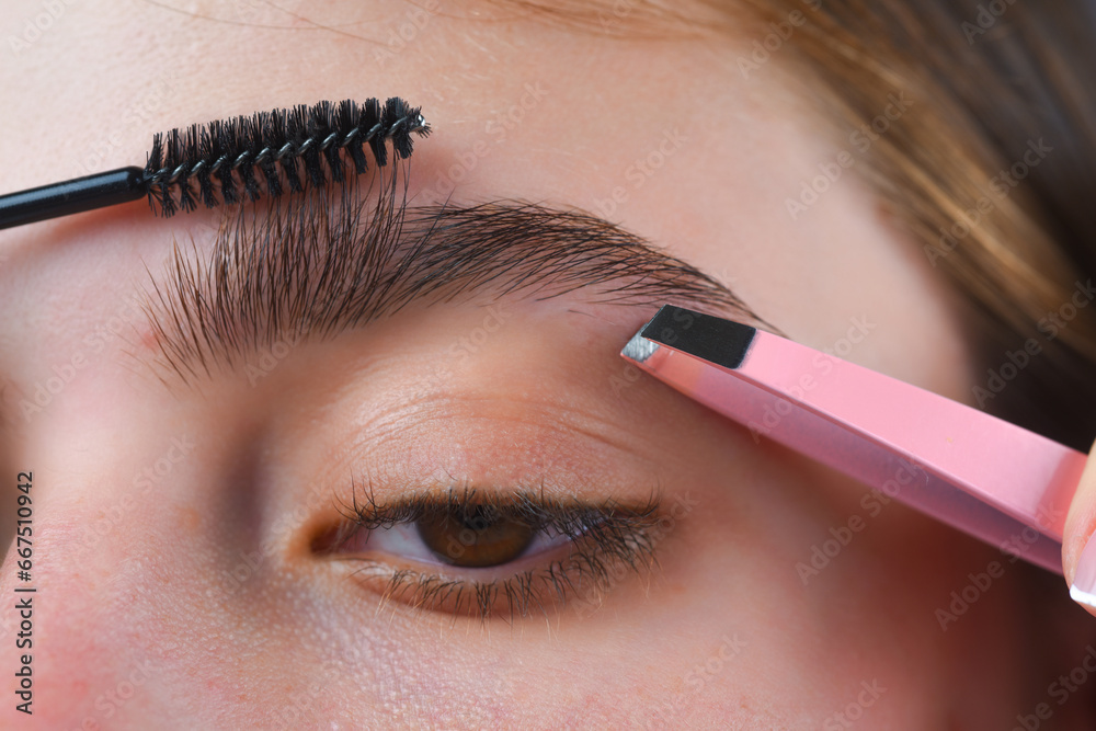 Perfect eyebrows. Close up of woman getting eyebrow make-up. Macro applying cosmetics on her eyebrow with brush. Perfect shape of eyebrow, brown eyeshadows and long eyelashes. Shape eyebrows.