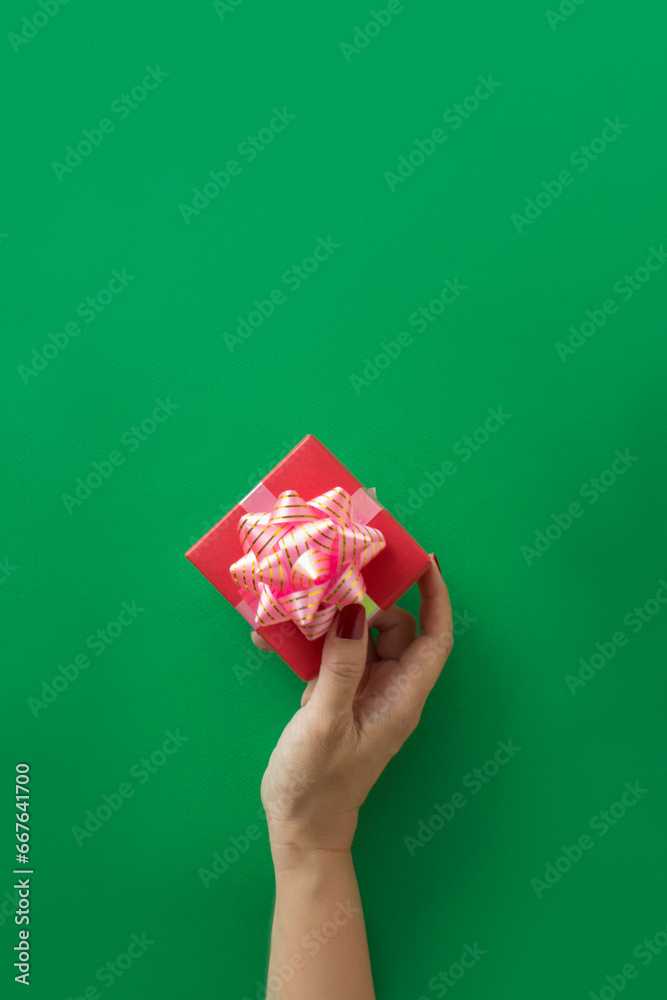 Hand holding a gift boxe on green background.