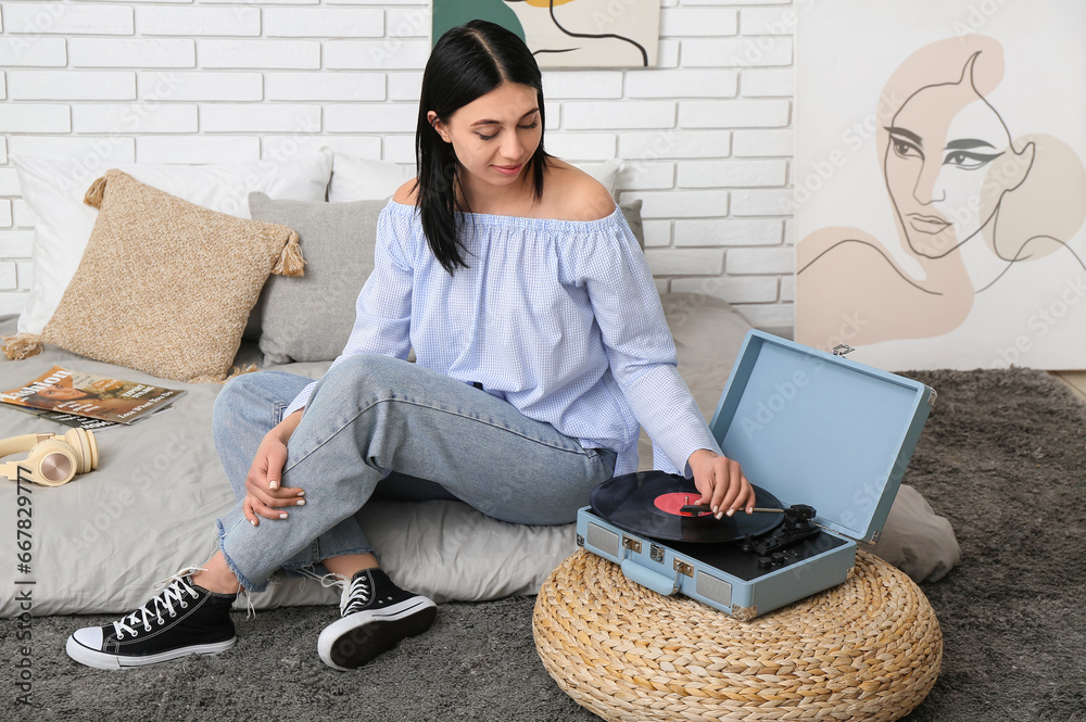 Young woman with record player in bedroom