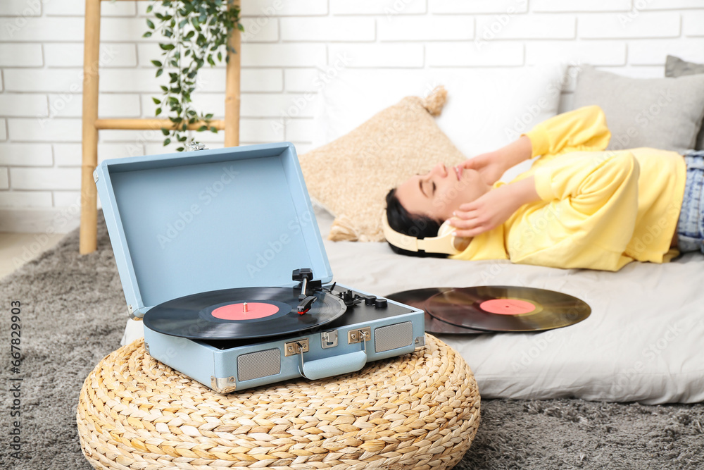 Young woman with headphones and record player in bedroom, closeup