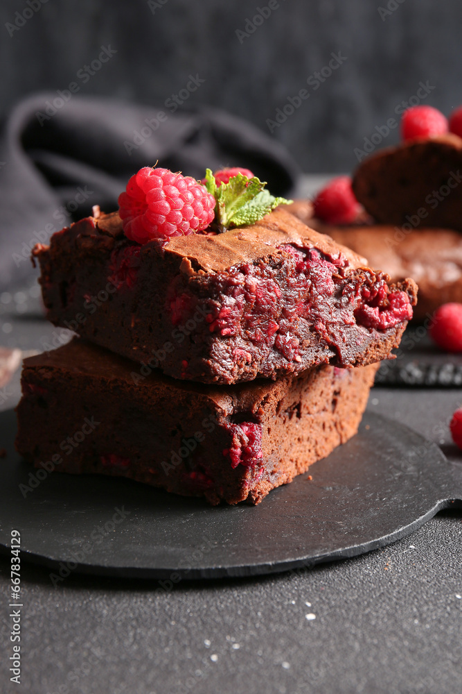 Board with pieces of raspberry chocolate brownie on black table