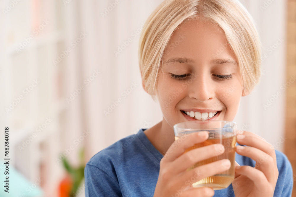 Little boy with glass of apple juice at home, closeup