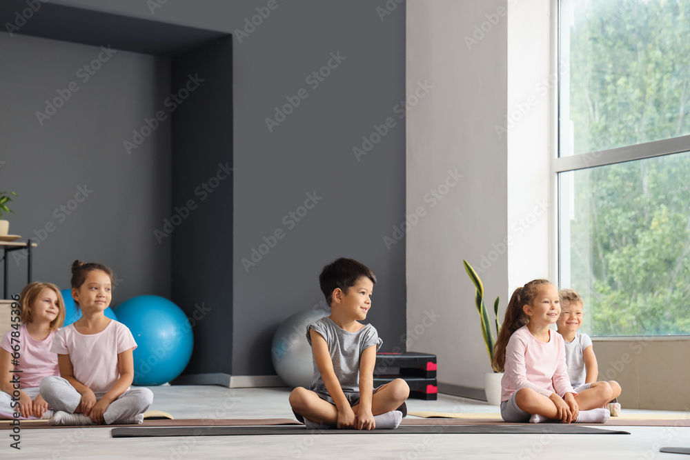 Group of little children practicing yoga in gym