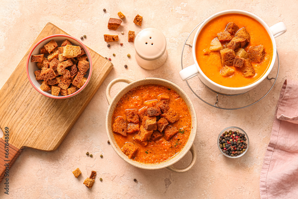 Pots of tasty cream soup with croutons on beige background