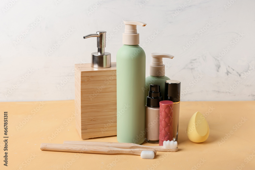 Set of cosmetic products, toothbrushes and makeup sponge on color table