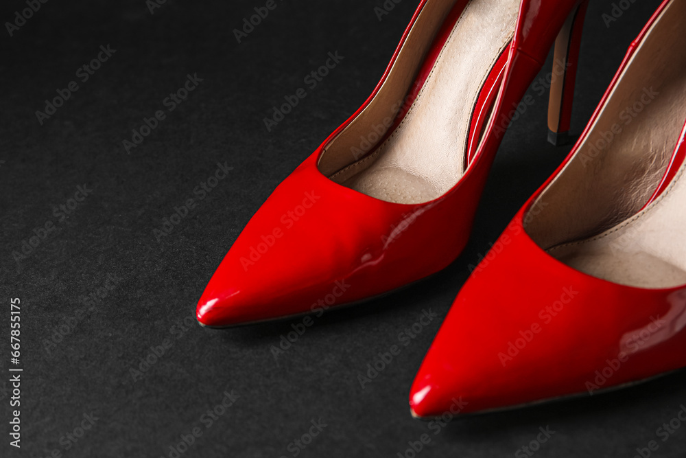 Stylish red high heels on black background