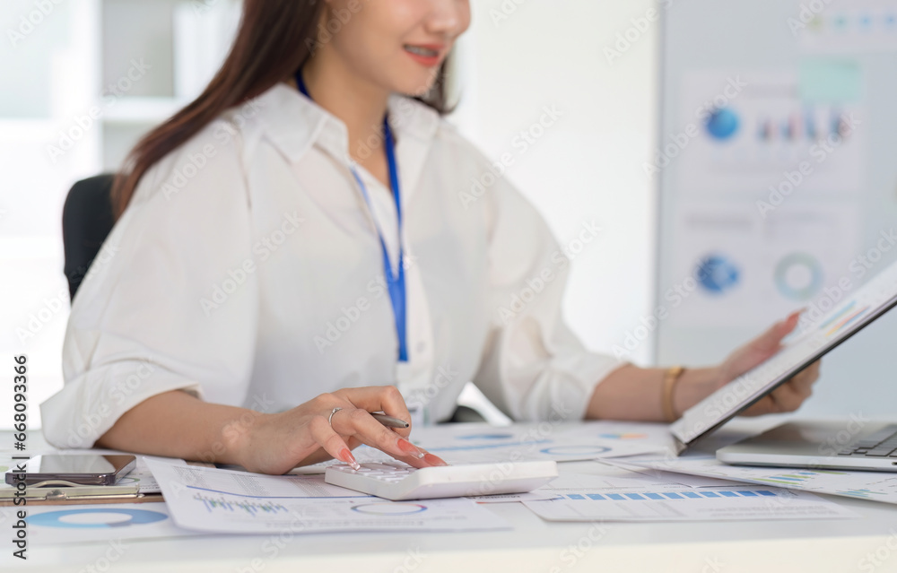 Businesswoman using calculator to do finance, mathematics on white table in office and business background, graph, tax, accounting, statistics and analytical research concept.