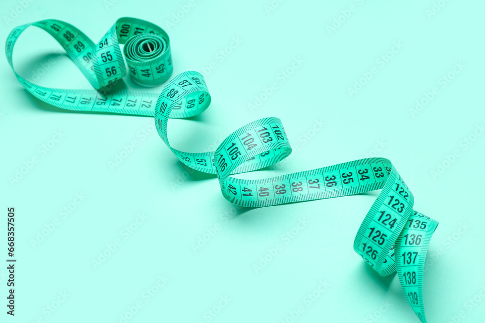 New measuring tape on turquoise background, closeup