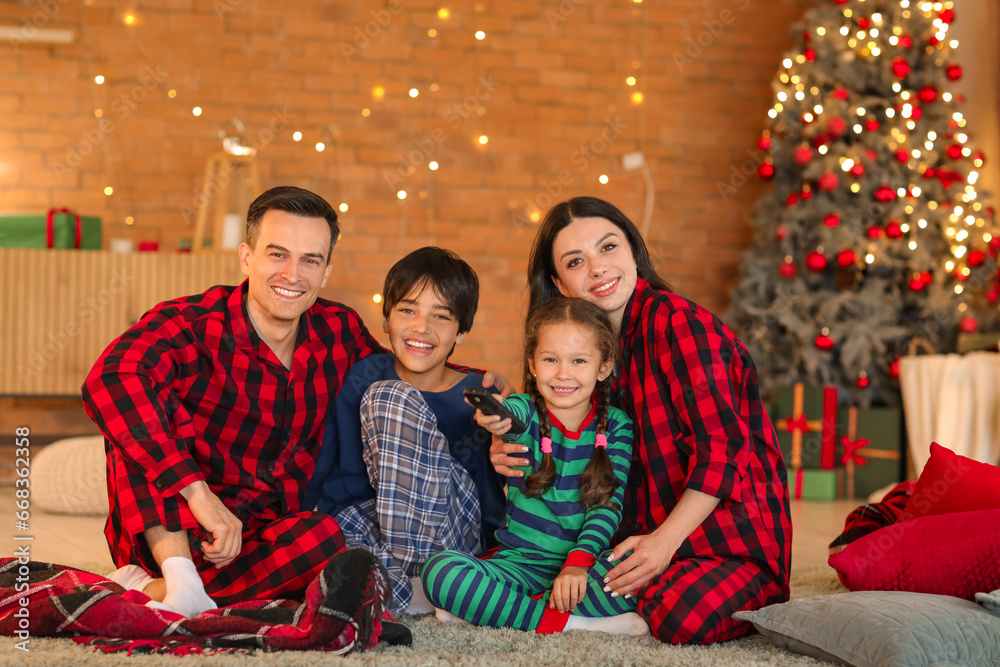 Happy family watching Christmas movie on TV at home