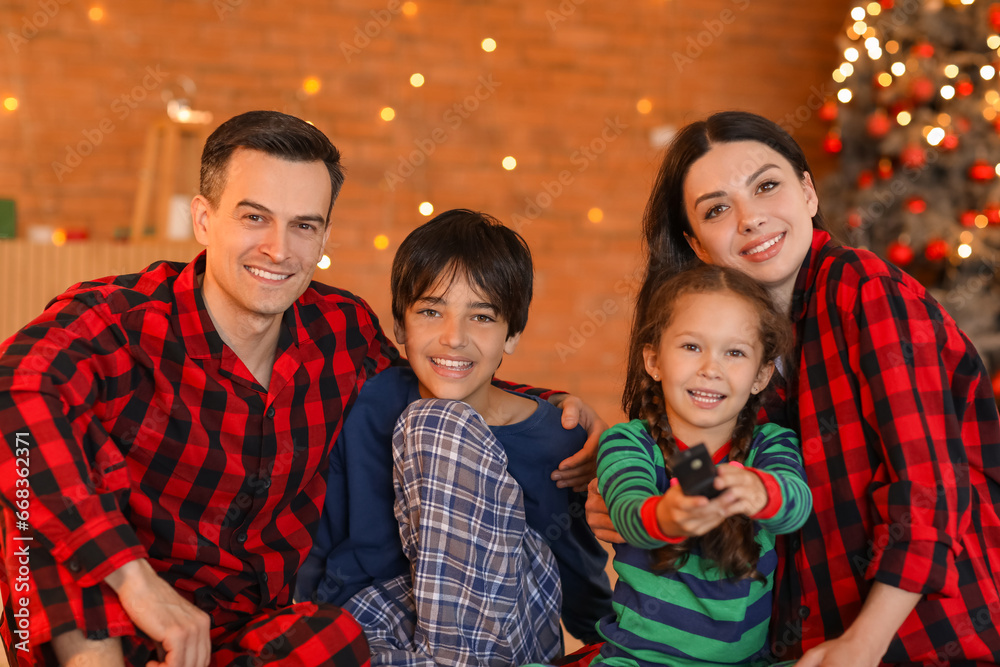 Happy family watching Christmas movie on TV at home