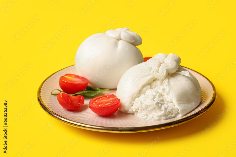 Plate with tasty Burrata cheese on yellow background