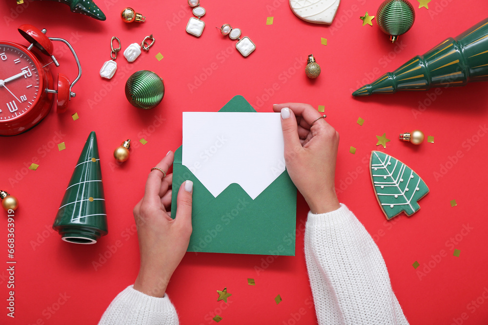 Woman with blank card and Christmas decor on red background