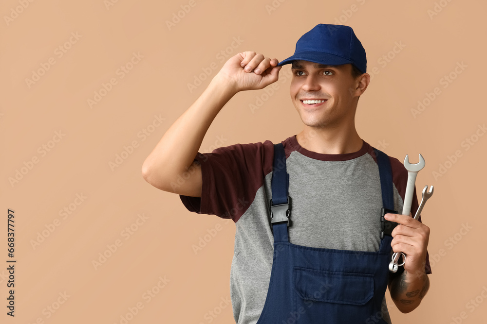 Male car mechanic with wrenches on beige background