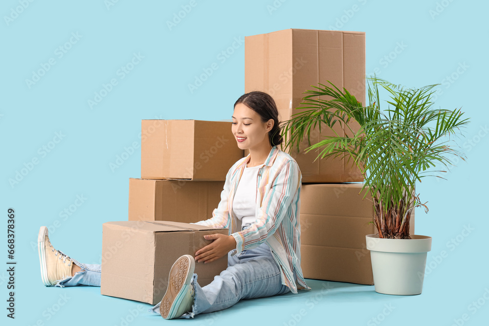 Young Asian woman with parcels on blue background