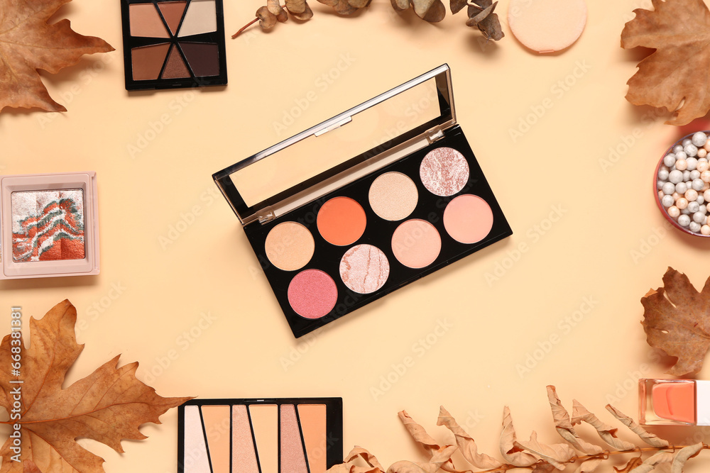 Composition with different eye shadows palettes and autumn leaves on beige background