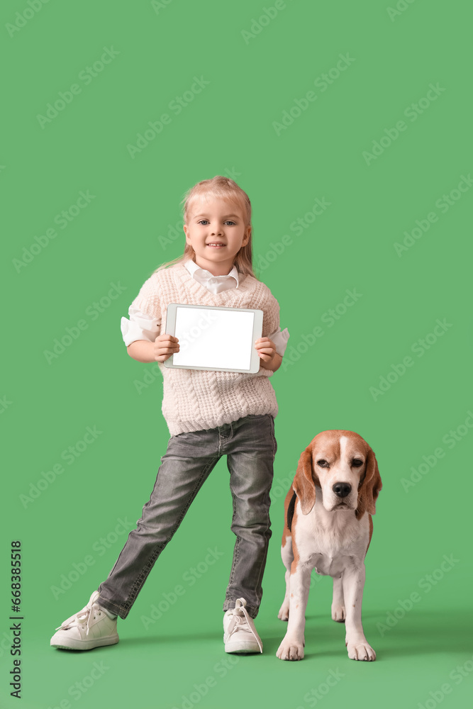 Cute little girl with tablet computer and Beagle dog on green background