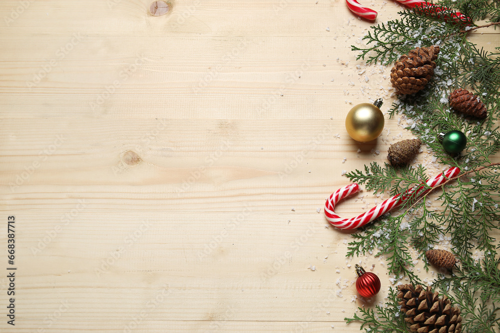 Christmas branches with decor and snow on light wooden background