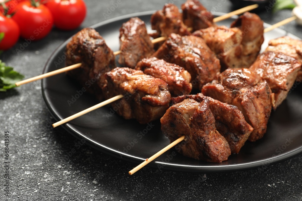 Skewers with delicious shish kebabs on grey textured table, closeup