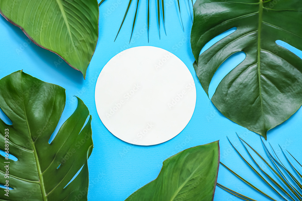 Blank card with different tropical leaves on blue background