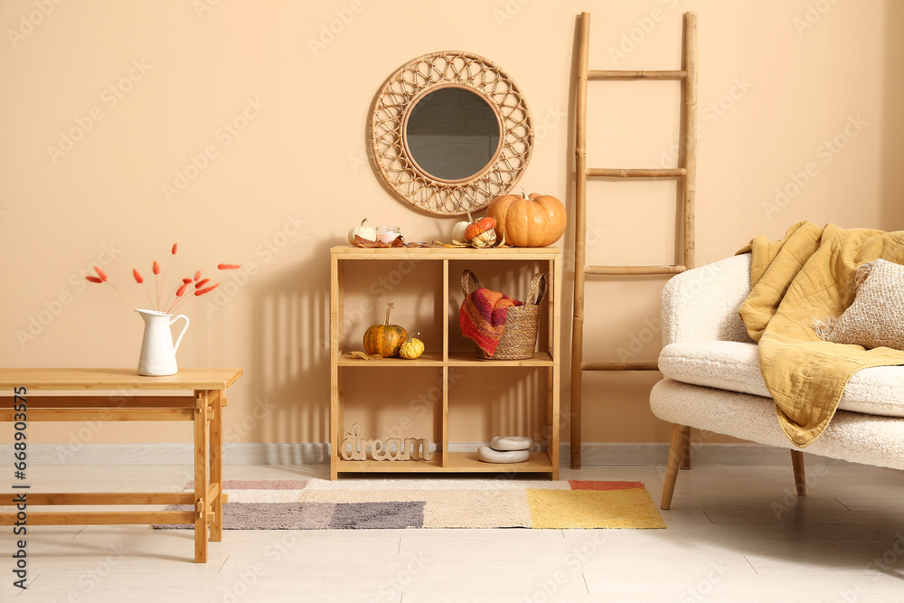 Interior of stylish living room with white sofa, coffee table and pumpkins on shelving unit