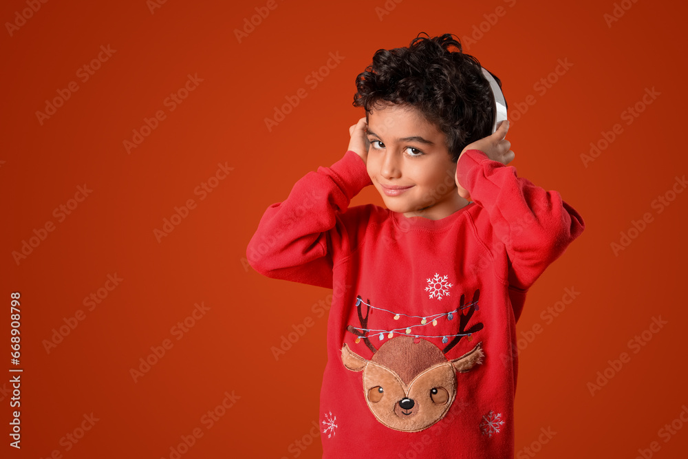 Cute little boy in headphones orange background