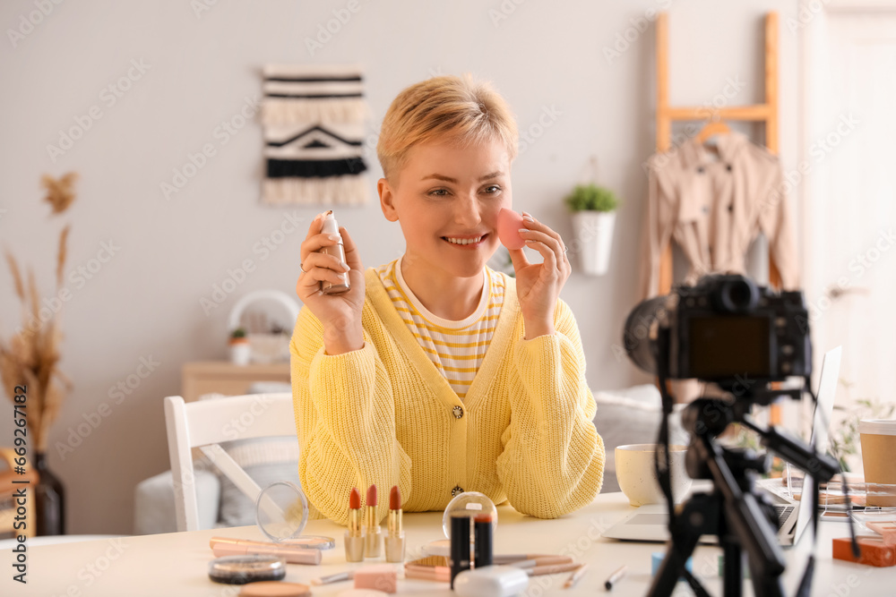 Female beauty blogger applying makeup foundation while recording video at home