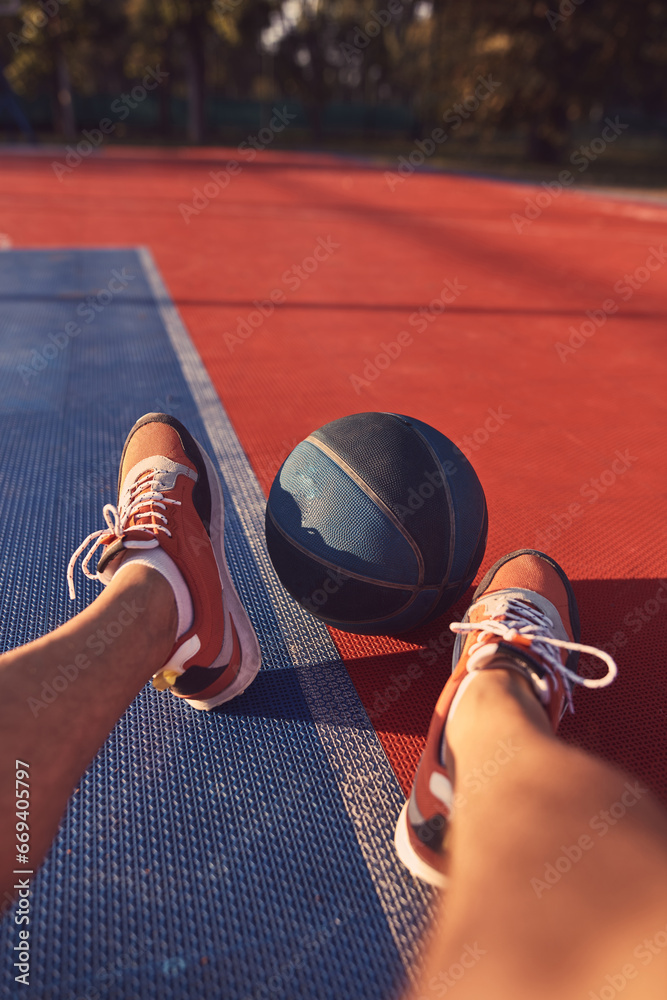 Man making pause after playing basketball on a open public court.