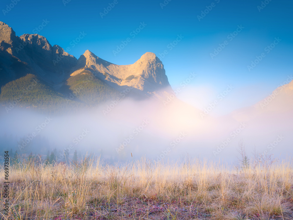 Fall landscape. Foggy landscape in the morning. Mountain peak. Sunbeams in a valley. Field in a mountain valley at dawn. Natural landscape.