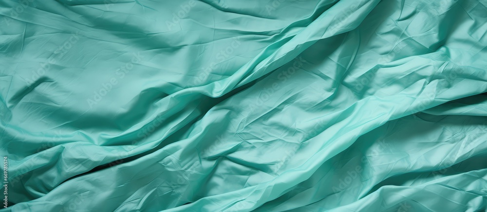 Closeup of crumpled green wrapping paper on light cyan background with white gradient Mint material backdrop