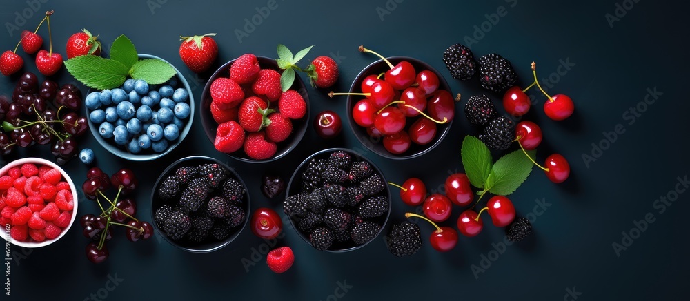 Summer fruit assortment including berries cherries plums and currants served with ice cream on a dark background with copy space