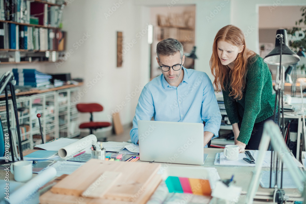 Two focused professionals discussing a project on a laptop in a modern workspace