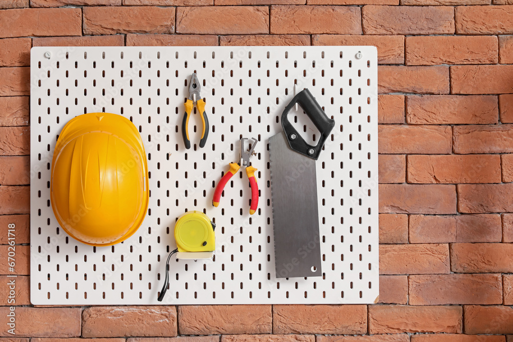 Pegboard with builders tools on brick wall in workshop