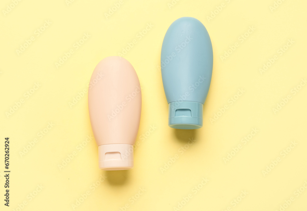 Bottles of travel cosmetic products on yellow background