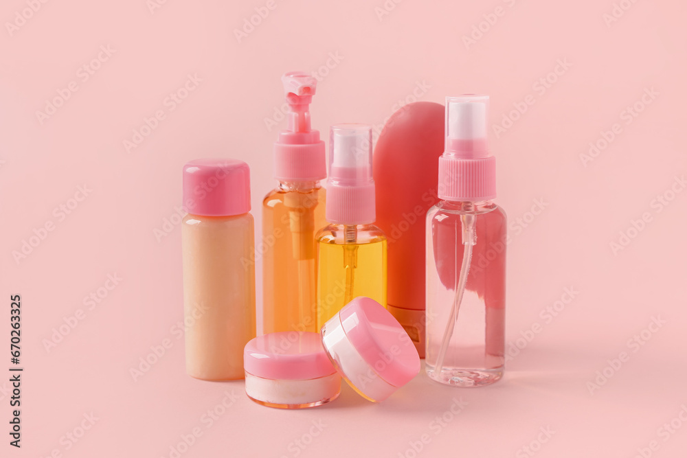 Set of travel cosmetic products on pink background