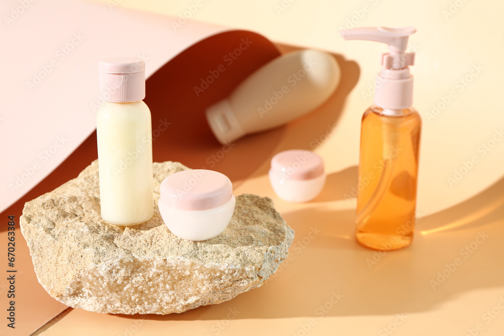 Stone with set of travel cosmetic products on color background